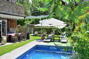 a pool with chairs and an umbrella next to a patio at Villa Vuchev in Velingrad