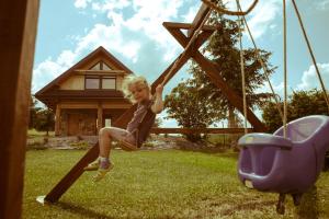 a young girl sitting on a swing in a yard at Domek "PRZYBYSZÓWKA" Bieszczady in Mchawa +54 photos