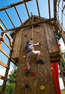a young boy is climbing up a climbing wall at Domek "PRZYBYSZÓWKA" Bieszczady in Mchawa