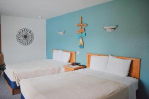 two beds in a room with blue walls at Innlet Motel in Sturgeon Bay