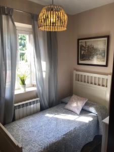 a bedroom with a bed and a window and a chandelier at CASA LUPITA in Cudillero