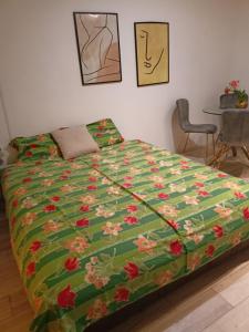 a bed with a green blanket with flowers on it at DUŠICA APARTMANI in Jagodina
