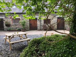 a wooden picnic table in front of a building at Bryn Melyn Farm Cottages in Bala