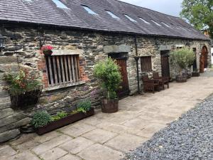 an old stone building with potted plants on it at Bryn Melyn Farm Cottages in Bala