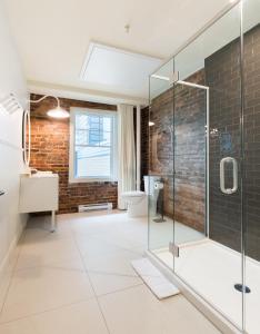 a bathroom with a glass shower and a brick wall at La Maison des Lofts - Par les Lofts Vieux-Quebec in Quebec City
