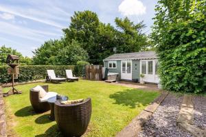 um jardim com um barracão e cadeiras e um quintal em The Summerhouse, countryside retreat with private hot tub em Bridgnorth