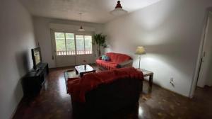 a living room with a red couch and a table at Apartamento com dois quartos no fragata in Pelotas
