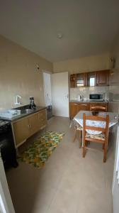 a kitchen with a sink and a table with a chair at Apartamento com dois quartos no fragata in Pelotas