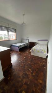 a bedroom with two beds and a wooden floor at Apartamento com dois quartos no fragata in Pelotas