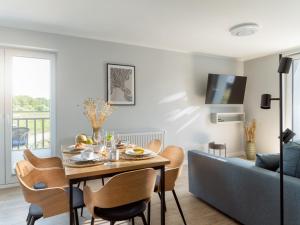 a living room with a table and a blue couch at Vincent Apartamenty Darłówek in Darłowo