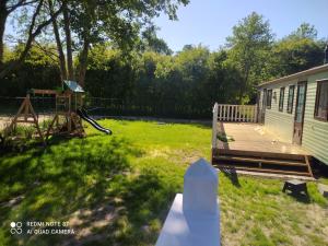 a backyard with a deck and a house at Karwia-Karwieńskie Błota domek przy plaży in Karwieńskie Błoto Drugie