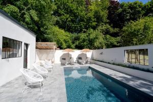 a swimming pool in a backyard with chairs and umbrellas at Domaine de la Course in Doudeauville