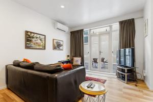 a living room with a leather couch and a tv at CBD Spacious 3 Storey Terrace House with Courtyard in Auckland