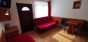 a living room with a red couch and a window at Pod Filarami Pobierowo in Pobierowo