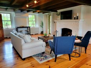 a living room with a couch and a fireplace at Downingtown Manor - 1900s Farmhouse with Creek Views in Downingtown
