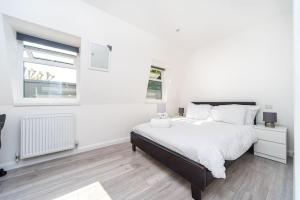 een witte slaapkamer met een groot bed en een raam bij Lovely 3 Bed Flat in a Great Location in London in Londen