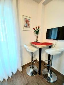 a room with a table and two stools and a television at Studio Apartmani Pomalo/ Take It Easy in Split