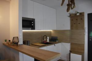 a kitchen with white cabinets and a wooden counter top at NAD LISIM JAREM in Jastrzębia Góra