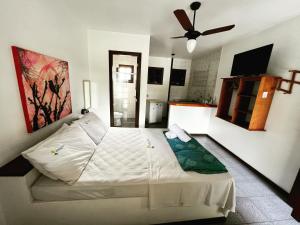 a white bed in a room with a ceiling fan at Búzios Flat Pousada in Búzios