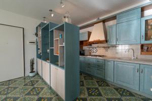 a kitchen with blue cabinets and a tile floor at DOLF - Attico sul Mare in Porto Recanati