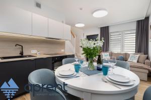 a kitchen and living room with a white table and chairs at Dom Sosnowe Zacisze Horizon Park - Aprent in Dziwnówek