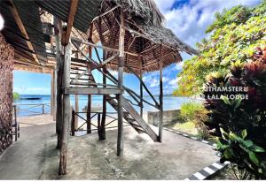 Lala lodge Pemba Zanzibar في Mgini: منتجع فيه مظله من القش والمحيط