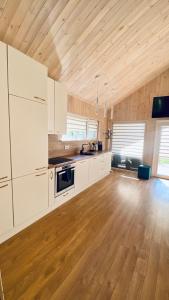 a large kitchen with white cabinets and wooden floors at Chill House in Anykščiai