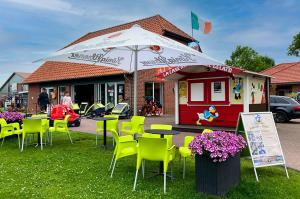 un restaurant avec des tables, des chaises et un parasol dans l'établissement HP Touristik - Seepark Burhave 7, à Butjadingen 32 autres photos