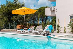 un gruppo di sedie e un ombrellone accanto alla piscina di Holiday Home Quadro Rabac a Rabac