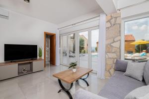 un soggiorno con una TV, un divano e un tavolo di Holiday Home Quadro Rabac a Rabac