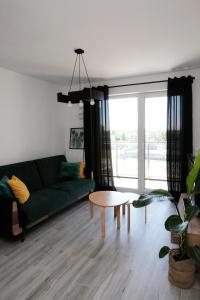 een woonkamer met een groene bank en een tafel bij Apartament Tramwajowa 17B in Łódź