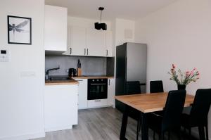a kitchen with a wooden table and black appliances at Apartament Tramwajowa 17B in Łódź