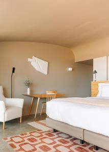 a bedroom with a bed and a table and a chair at Immerso Hotel, a Member of Design Hotels in Ericeira