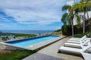 a swimming pool with two lounge chairs and the ocean at Happy Days Villa B in Fajardo