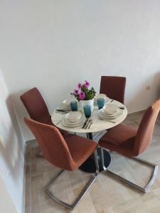 uma mesa branca com cadeiras e um vaso de flores em Apartman Bartol em Skradin