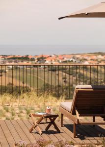- une chaise longue et une table basse sur une terrasse donnant sur l'océan dans l'établissement Immerso Hotel, a Member of Design Hotels, à Ericeira