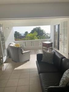 a living room with two couches and a balcony at Petals Lovely Beach Villa in Saint Johnʼs
