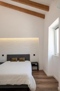 um quarto com uma cama com paredes brancas e pisos em madeira em Casa Monte dos Entrudos em Almancil