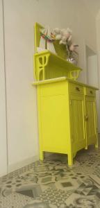 a yellow cabinet with flowers on top of it at Poggiamico Guest House in Favignana