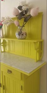 a yellow cabinet with a vase with flowers in it at Poggiamico Guest House in Favignana