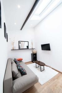 Una sala de estar con un sofá y un televisor. en La Luna - Élégante Maison de Standing avec extérieur - 25 min de Paris, en Andrésy
