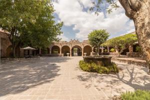 une cour avec des arbres et un bâtiment en briques dans l'établissement Hacienda El Salitre Hotel & Spa, à Querétaro