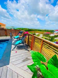 a deck with a chair and a swimming pool on a balcony at Villa Passion Cannelle de standing avec sa piscine vue mer in Les Trois-Îlets