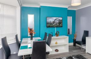 里茲的住宿－Leeds city centre spacious house free parking and Wi-Fi，一间拥有蓝色墙壁和桌椅的用餐室