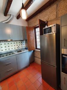 a kitchen with a stainless steel refrigerator and a sink at Casa do Cruzeiro in Aguiar da Beira