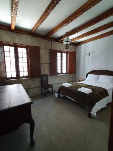 a bedroom with a bed and a table and windows at Casa do Cruzeiro in Aguiar da Beira