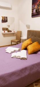 un letto viola con asciugamani e cuscini sopra di B&B VENTO DEL SUD a Palermo
