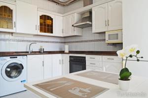 a white kitchen with a sink and a dishwasher at Viento Norte - Amplia terraza y chill out para quienes buscan descanso y calidez in San Vicente de la Barquera