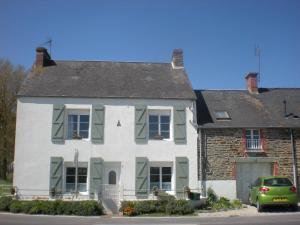 Biały dom z zielonymi okiennicami i samochód zaparkowany przed budynkiem w obiekcie Les Voiles Vertes w mieście Moidrey