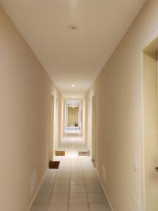 um corredor vazio com paredes brancas e um tecto longo em Apartamento Vivendas do Eucalipto em Petrópolis